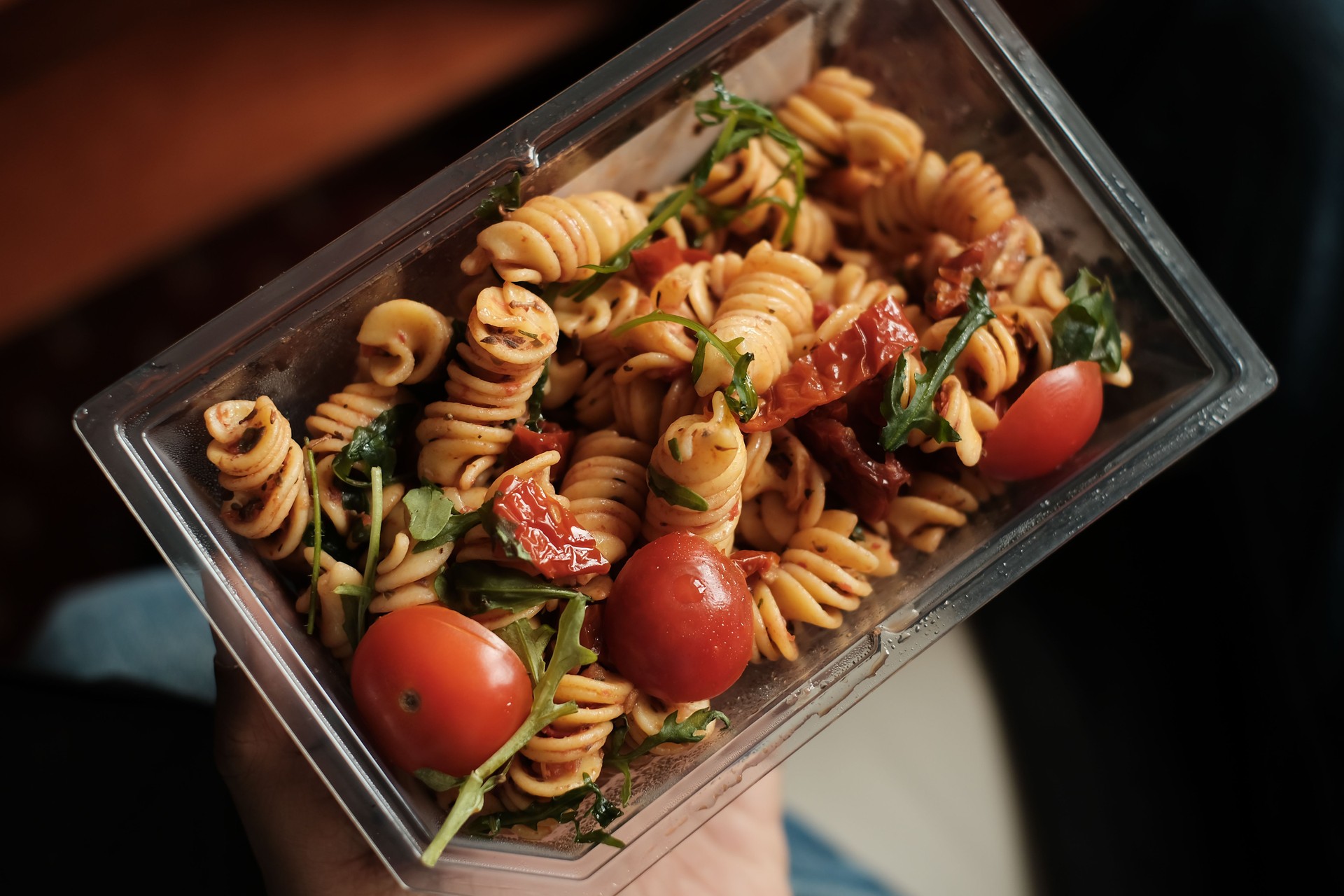 healthy pasta in take-away or to-go  plastic recycle container with wooden fork.  healthy lunch box concept